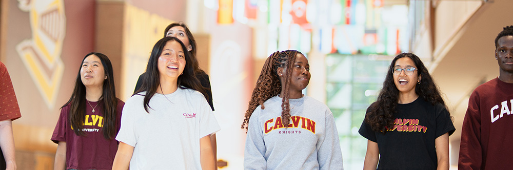 Calvin students walking in the Spoelhof Fieldhouse Complex under the international flags