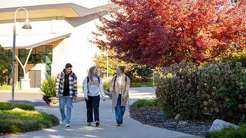 Calvin university students walking by the Spoelhof Fieldhouse Complex on campus
